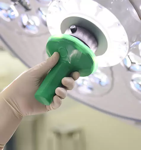 Close up of hand holding the Cleanview sterile handle cover on the Skytron Aurora Four surgical light